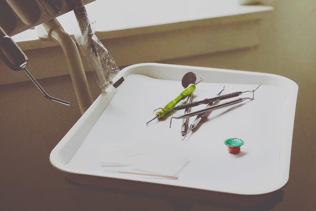 Dental instruments on a tray with polish paste in a small cup